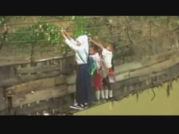 片方のロープが切れた橋を渡る子供たちの命懸の通学風景。インドネシア