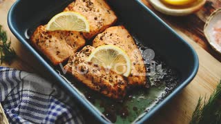 Roasted salmon in heat proof dish With aromatic dill lemon salt and pepper on sides