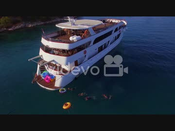 Swimmers and partiers jump off a large yacht or boat