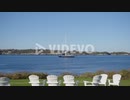 Sailboat passing by in the ocean just offshore from a resort in Newport Rhode Island