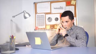 Young businessman is vaping e-sigaret while talking on the phone