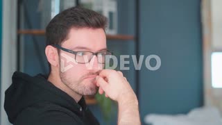 Pensive young man sitting pondering in living room