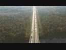 A car driving on a straight road surrounded by nature