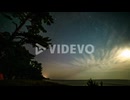The moon rising on a starry night colors of the aurora borealis in the sky - time lapse