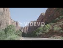 a road with a mountain range and bicyclists riding down