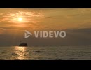 Sailing ship in quiet sea at sunset