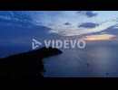 Aerial view of the ocean and mountain, with a boat and the sunset