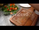 Person Placing The Slice Cherry Tomatoes In A Salad Bowl With Green Leaves