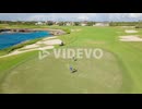 Aerial orbiting shot of couple playing golf on luxury golf course with Caribbean Sea in background