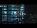 Descending shot along brightly illuminated construction site of modern high rise building at night