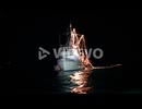 A fishing boat is illuminated on the water at night