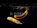 A set of ripe bananas being dropped into water in slow motion