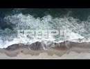 aerial view of ocean waves crashing on sandy beach