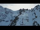 Aerial steep snow icy mountain top slope flying towards snowy summit on sunny day, alpine landscape